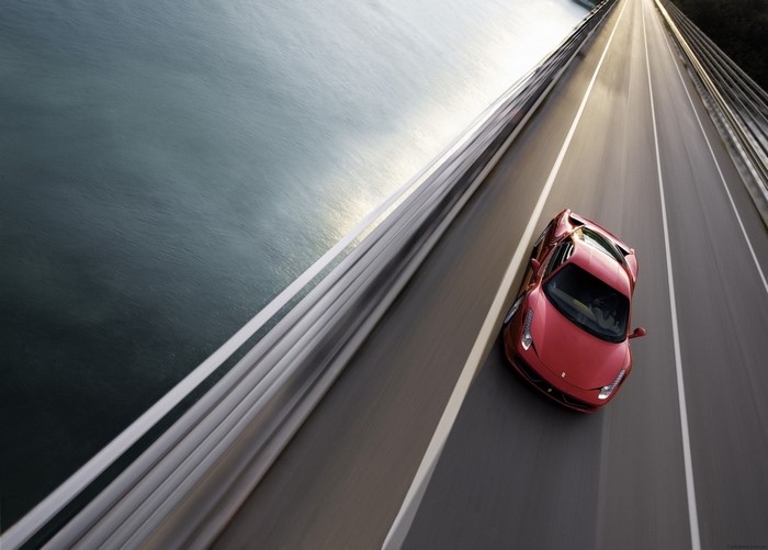 Red Ferrari 458 Italia driving on a bridge