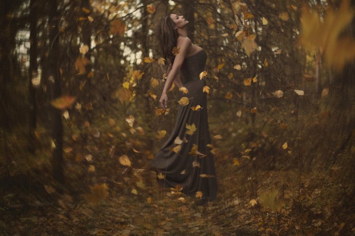 Woman in a dress in a forest with falling leaves