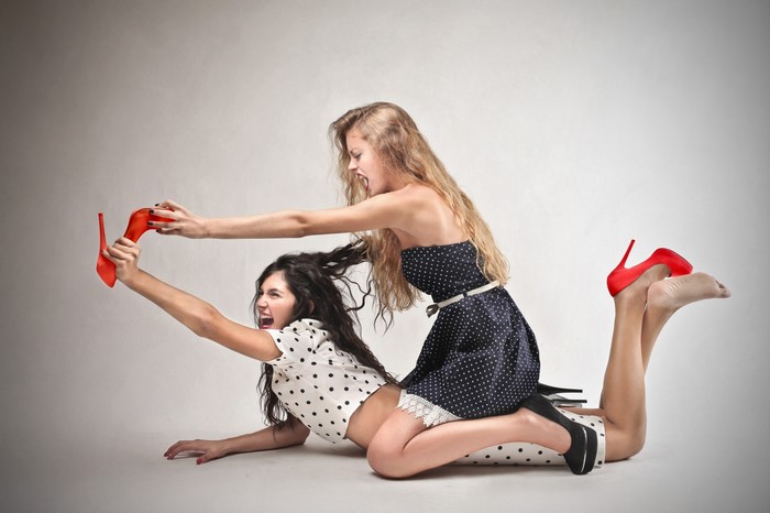 Two Women Engaged in Playful Shoe Tug-of-War