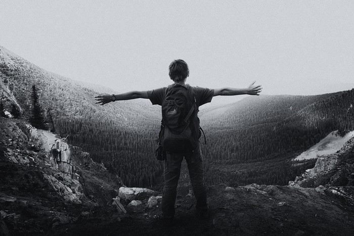 Person with backpack on mountain overlooking forest