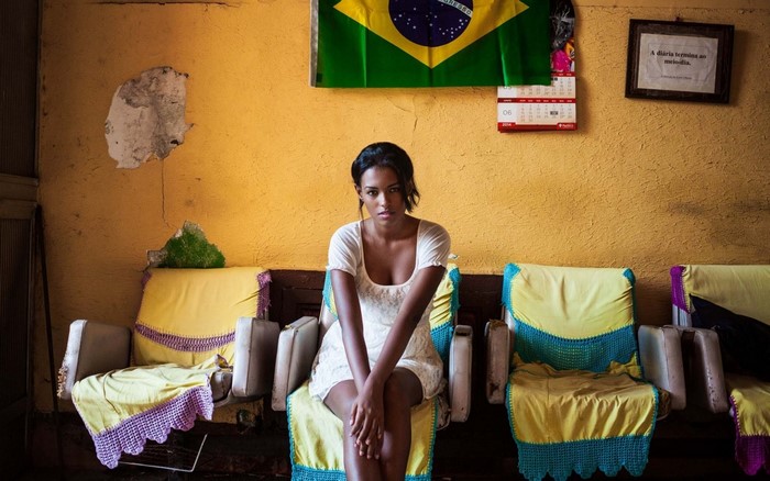 Woman in white dress sitting in front of Brazilian flag