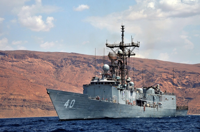 USS Oliver Hazard Perry (FFG-7) warship sailing near a rocky coast
