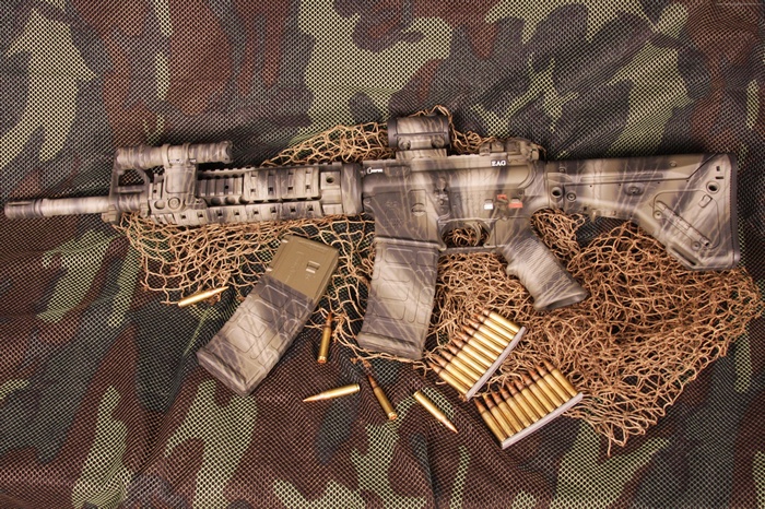 Camouflaged AR-15 rifle with magazines and ammunition