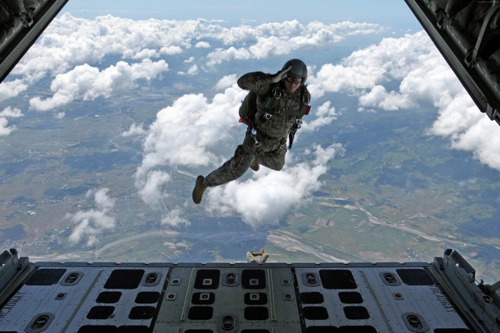 Soldier parachuting from an aircraft over clouds