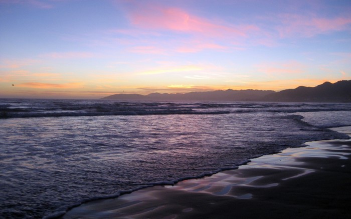 Sunset over the ocean with mountains on the horizon