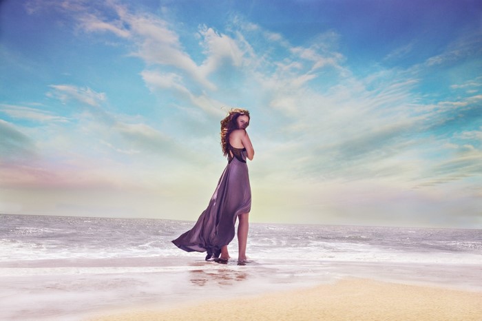 Woman in flowing dress on a beach at sunset