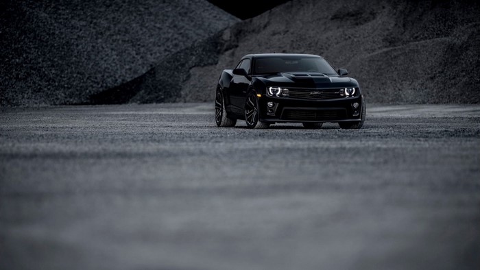 Black Chevrolet Camaro parked on gravel