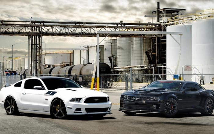 White Ford Mustang and Black Chevrolet Camaro at Industrial Site