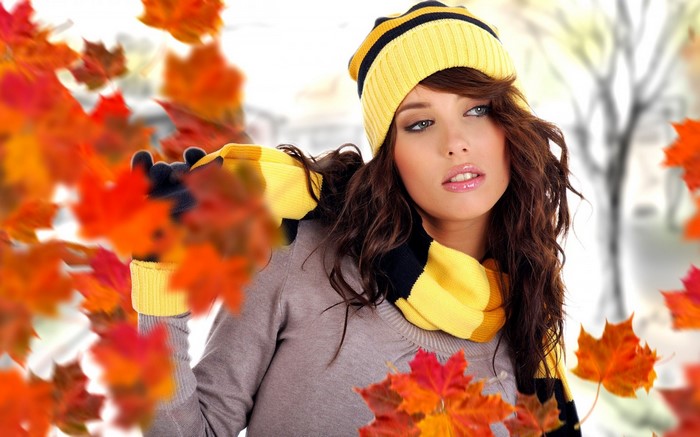 Woman in yellow hat and scarf with falling autumn leaves