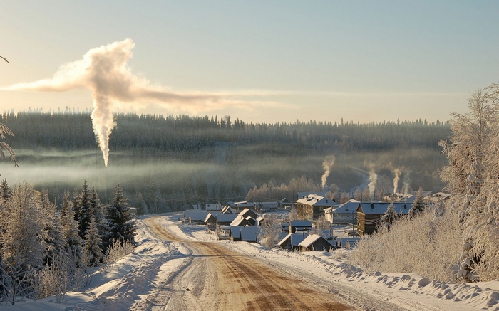 Winter village with smoke rising from chimneys