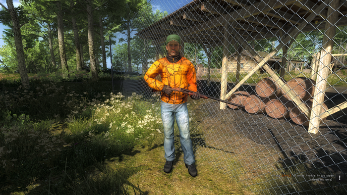 Man in orange jacket holding a rifle in a forest
