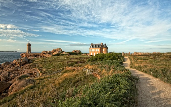 Lighthouse and house on a rocky coast with a path