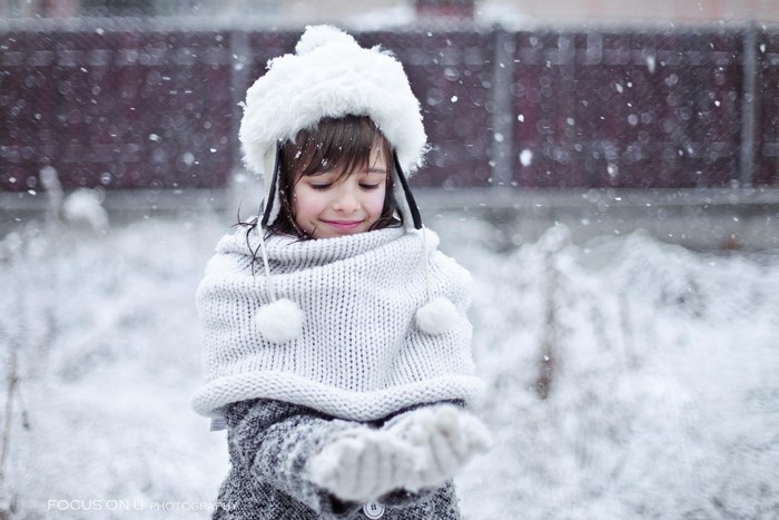 Young girl in winter hat and scarf catching snow