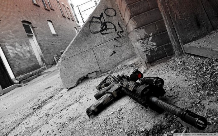 Assault rifle with red dot sight in alley