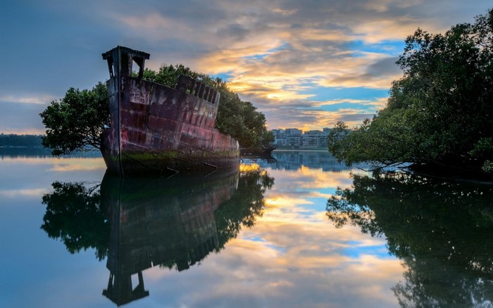 Abandoned shipwreck in a calm bay at sunrise