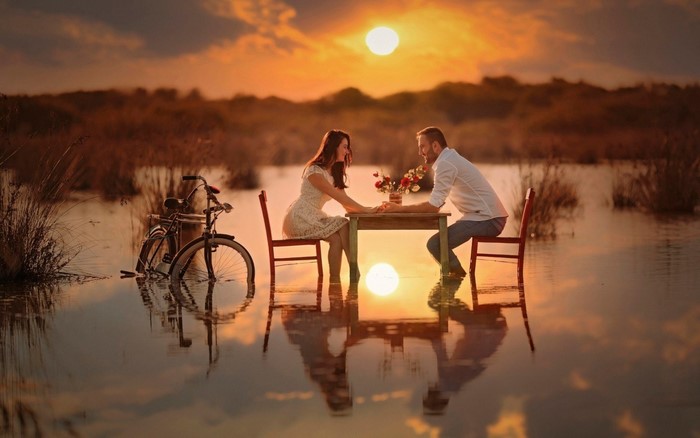 Couple having a romantic dinner by the water at sunset