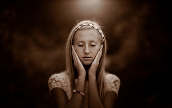 Young woman with hands on face, sepia tone
