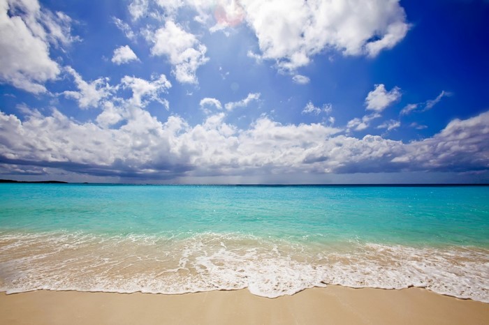 Sandy beach with turquoise ocean and cloudy sky