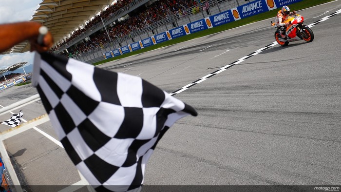 Motorcyclist crosses finish line with checkered flag
