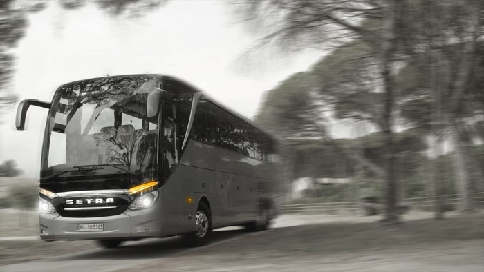 Setra bus driving on a road with trees