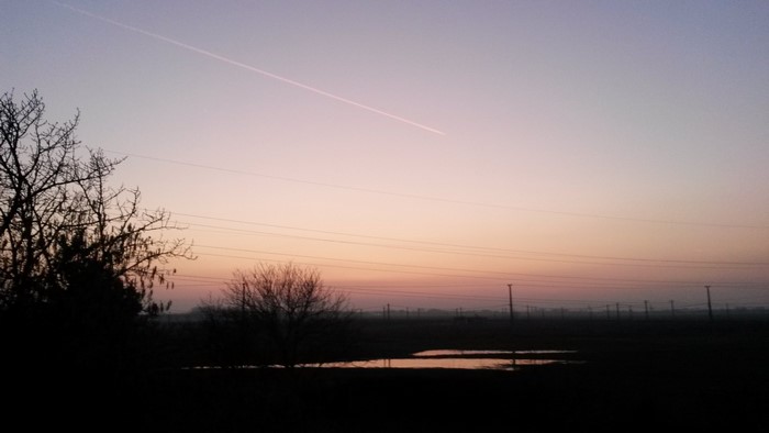 Sunset over a misty field with power lines