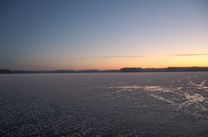 Frozen lake at sunset with distant treeline