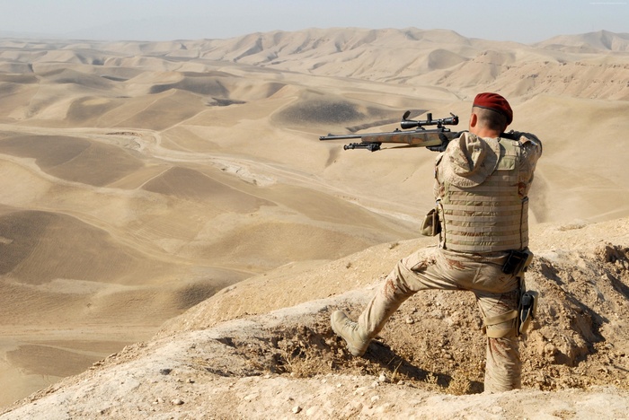 Soldier with sniper rifle in desert landscape