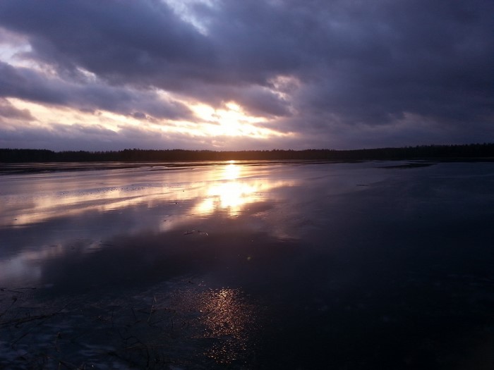 Sunset over a frozen lake with reflections