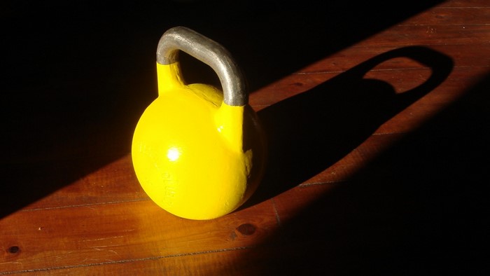 Yellow kettlebell on wooden floor with shadow