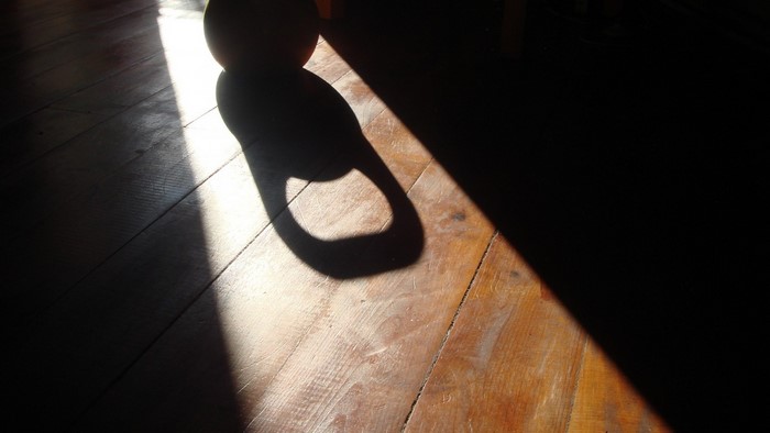 Shadow of a kettlebell on a wooden floor