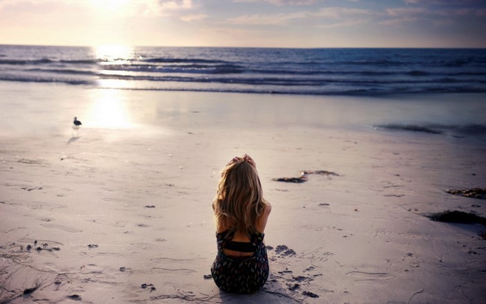 Woman sitting on a beach at sunset