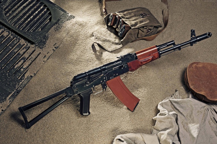 AK-74 assault rifle with ammunition bag on sand