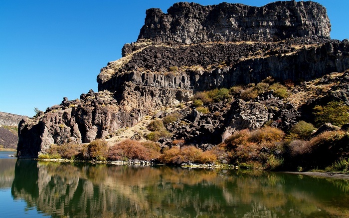 Rocky cliff face reflected in a calm lake