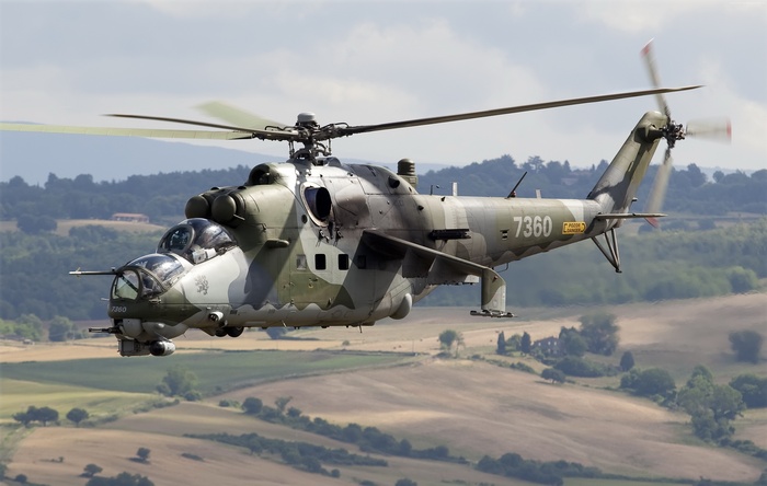 Mil Mi-24PN attack helicopter flying over rural landscape
