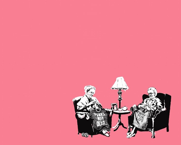 Two elderly women knitting with text on their creations