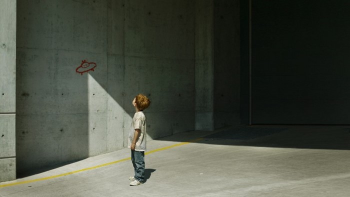 Child looking at UFO drawing on concrete wall