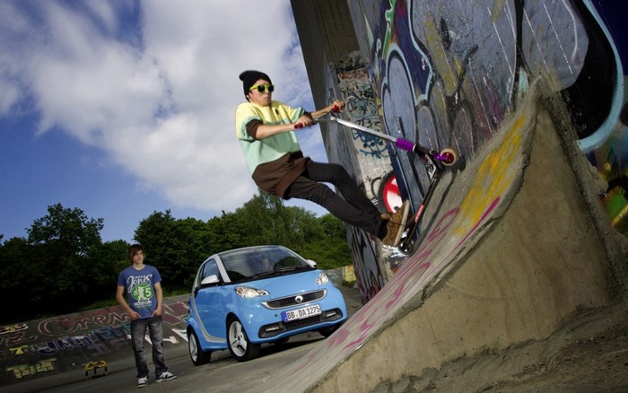 Boy on scooter near Smart car at skatepark