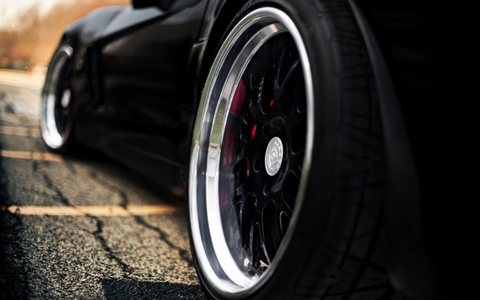 Black sports car wheel and tire on asphalt