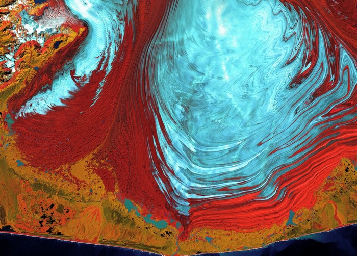 Aerial view of a glacier with red vegetation and water