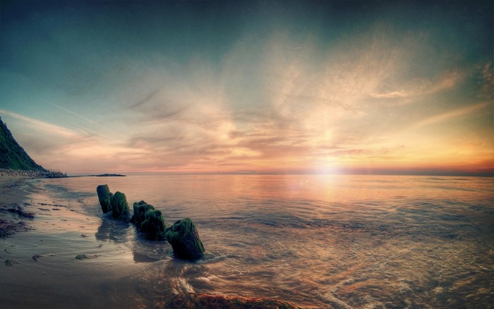 Sunset over the sea with wooden posts on the shore