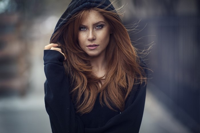 Woman with red hair and freckles wearing a black hoodie