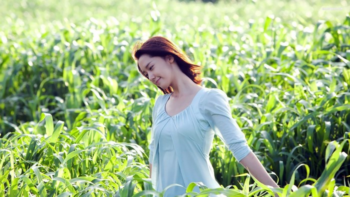 Woman in a light blue dress in a green field