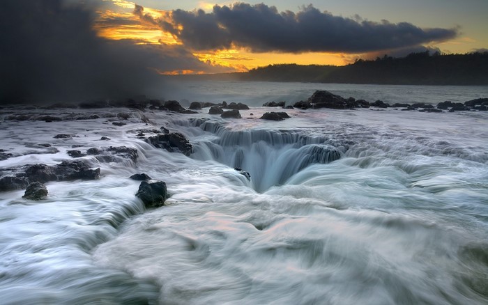 Ocean whirlpool at sunrise with dramatic clouds