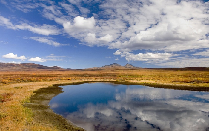 Autumn tundra landscape with a reflective pond and mountains