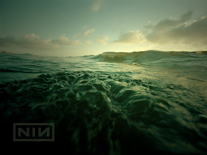 Nine Inch Nails logo over ocean waves at sunset