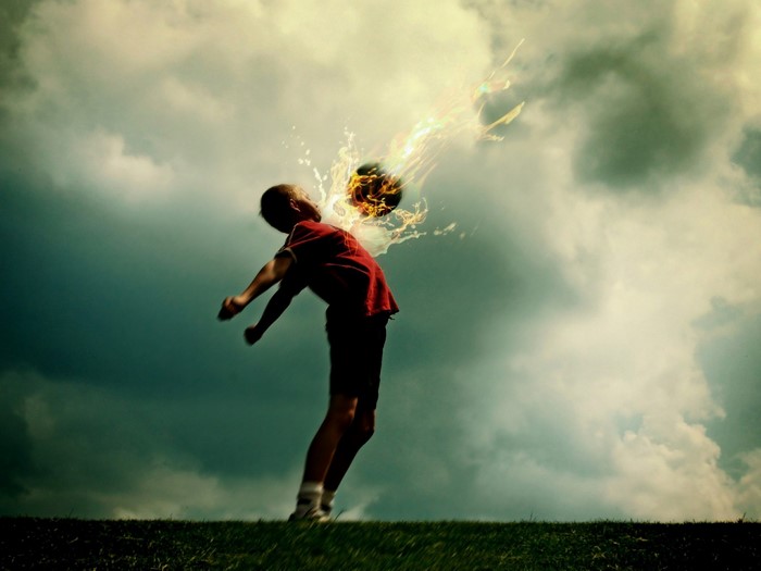 Boy heading a fiery soccer ball in the sky