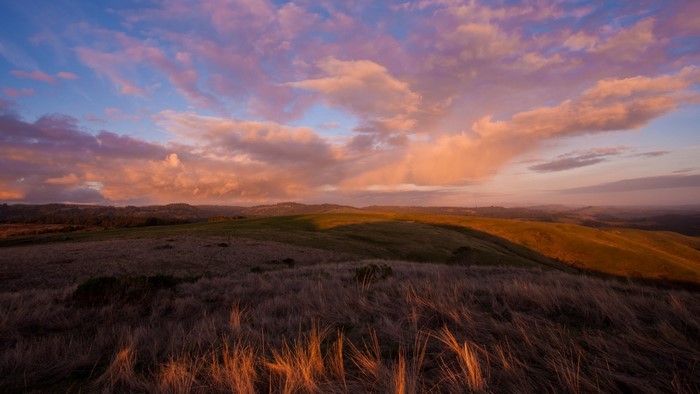 Sunset over rolling hills with dramatic clouds