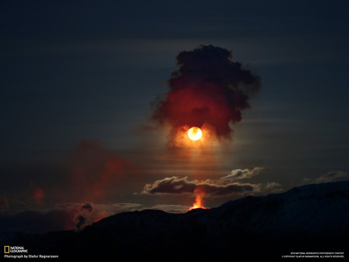 Volcanic eruption at sunset with sun obscured by smoke
