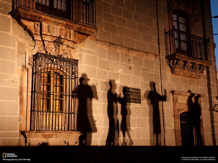 Shadows of people on a stone building