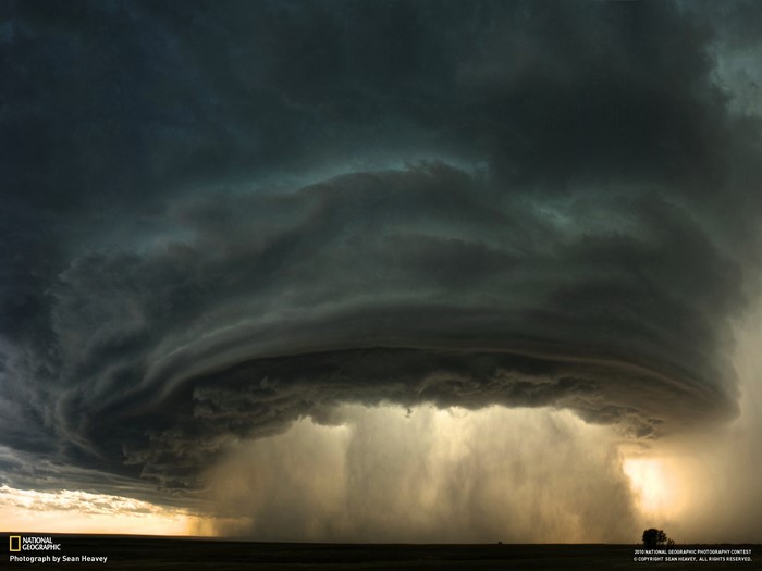 Storm clouds with rain and lightning over a field